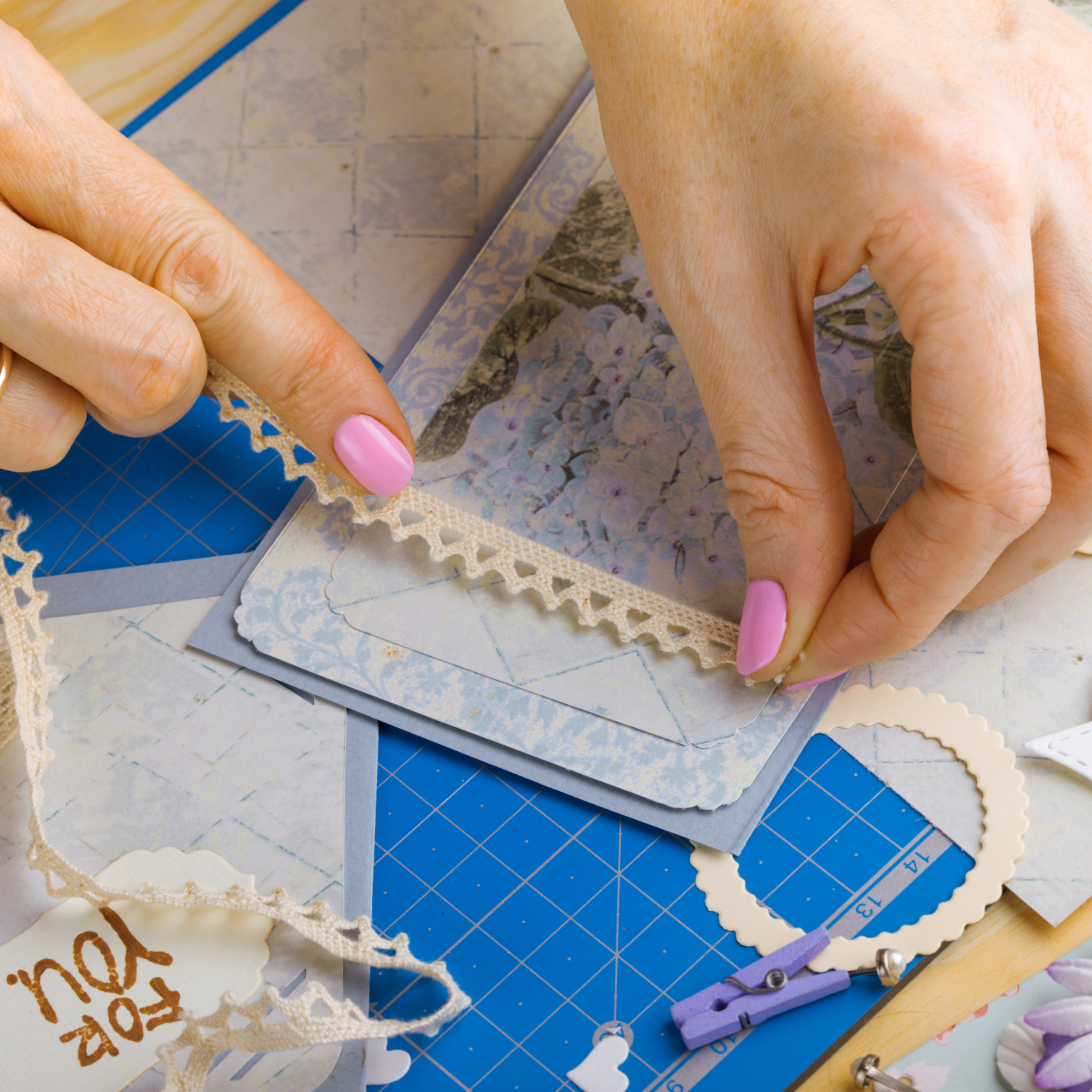 Photo of hands adding crafting material to a scrapbook page. 